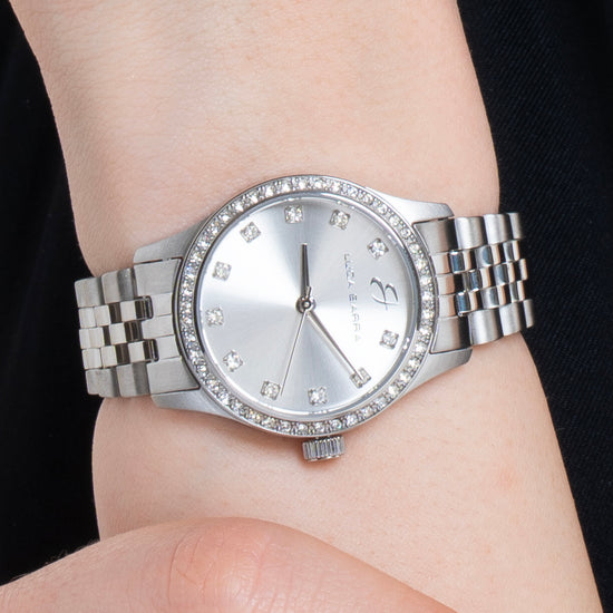 MONTRE EN ACIER POUR DAMES AVEC CADRAN ARGENTÉ ET LUNETTE EN CRISTAL BLANC